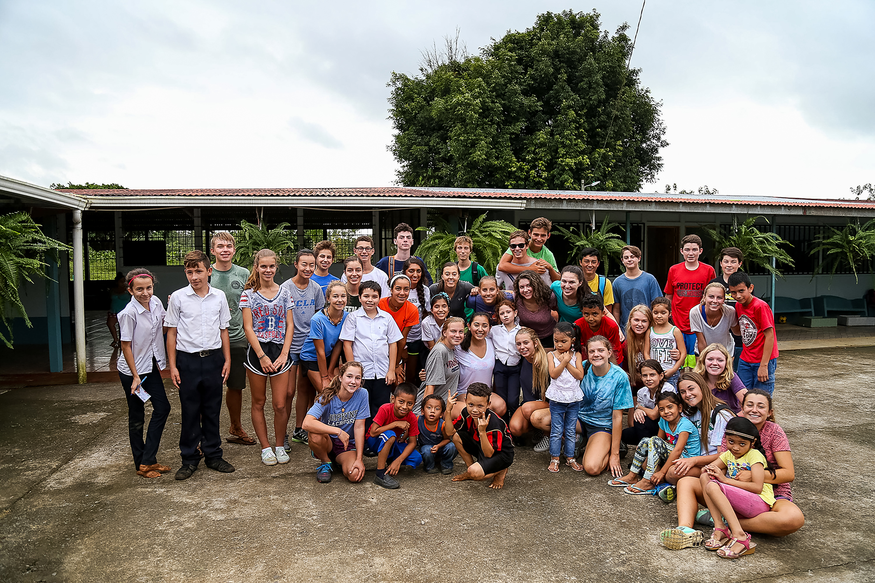 Students and local schoolchildren pose together outside a school building in Costa Rica