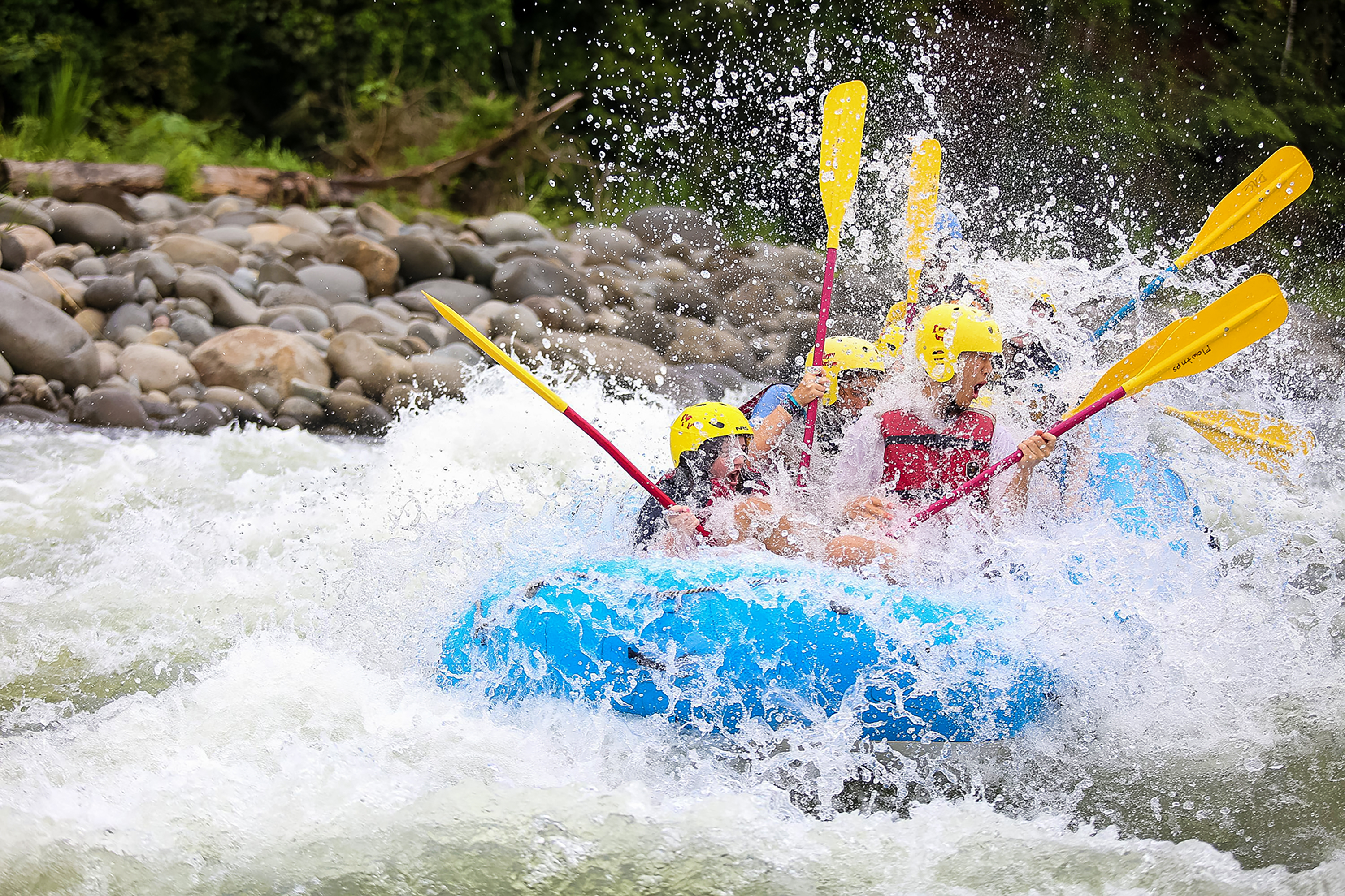 Students paddling a raft through whitewater rapids