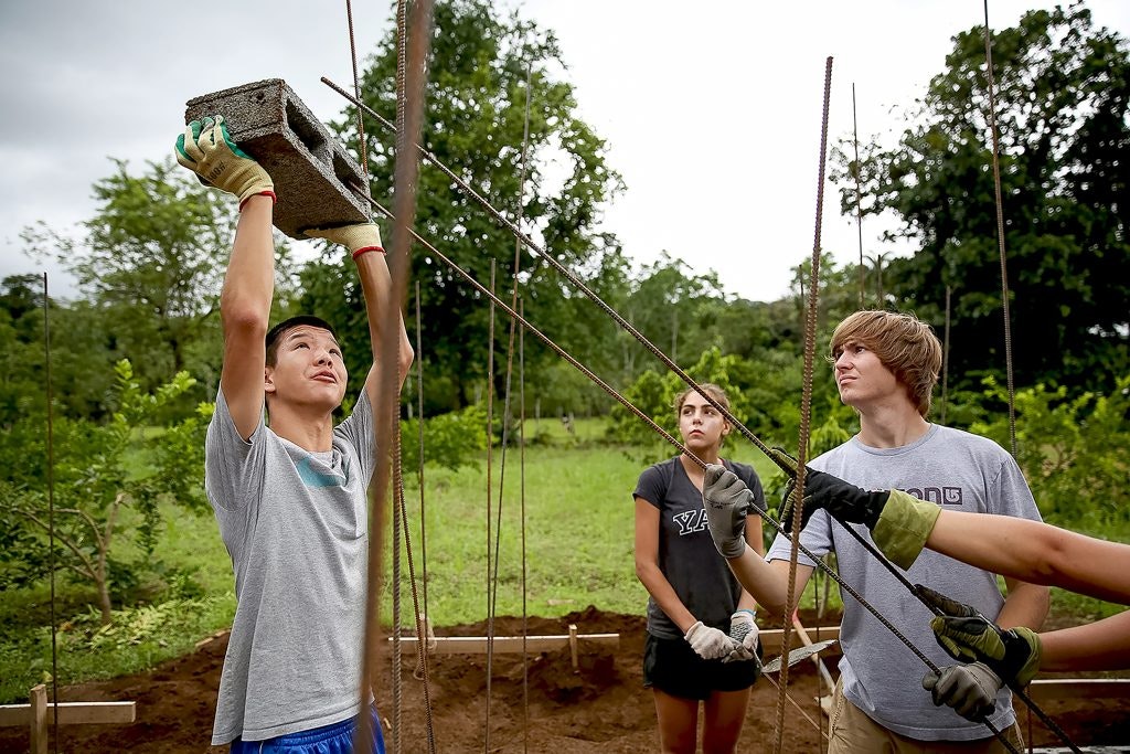 Students participating in a community service construction project during a life-changing trip for 16-year-olds.