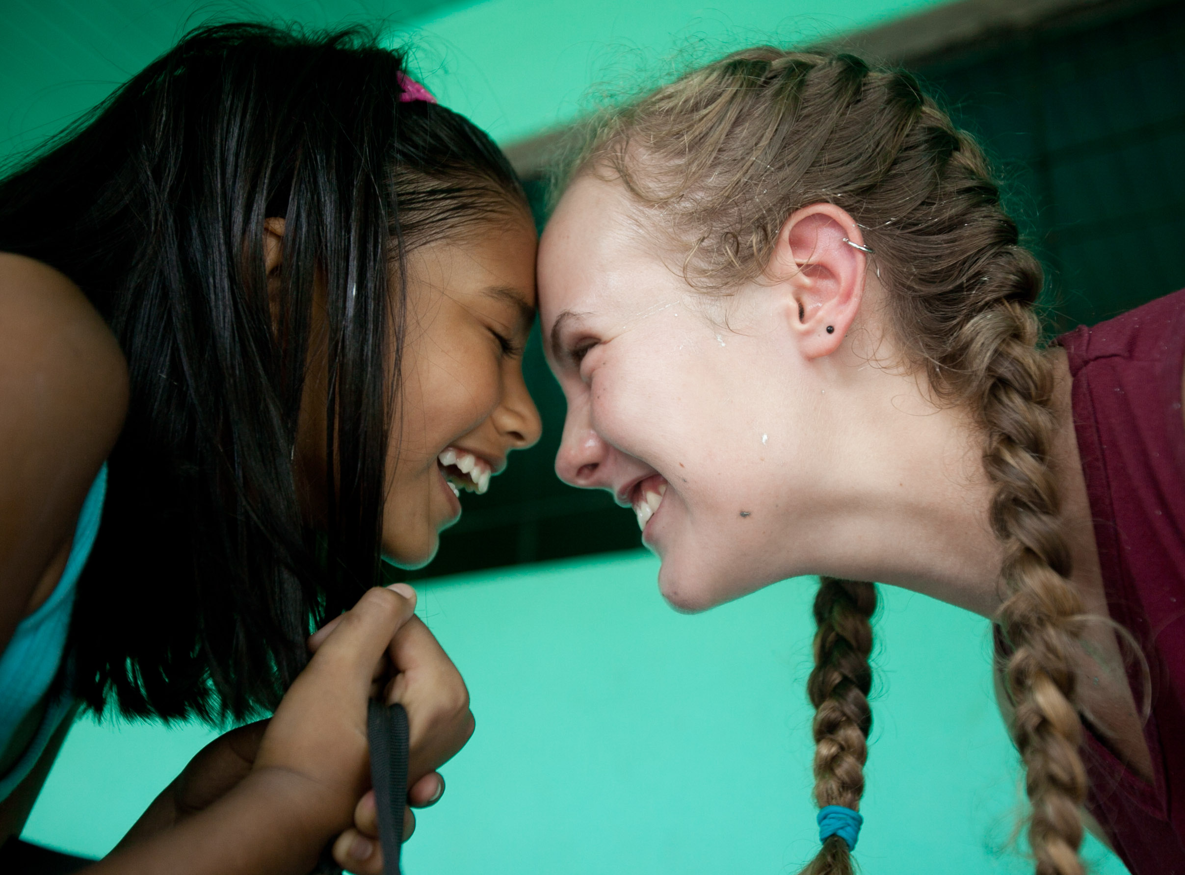 A student and a local girl touch foreheads, laughing together