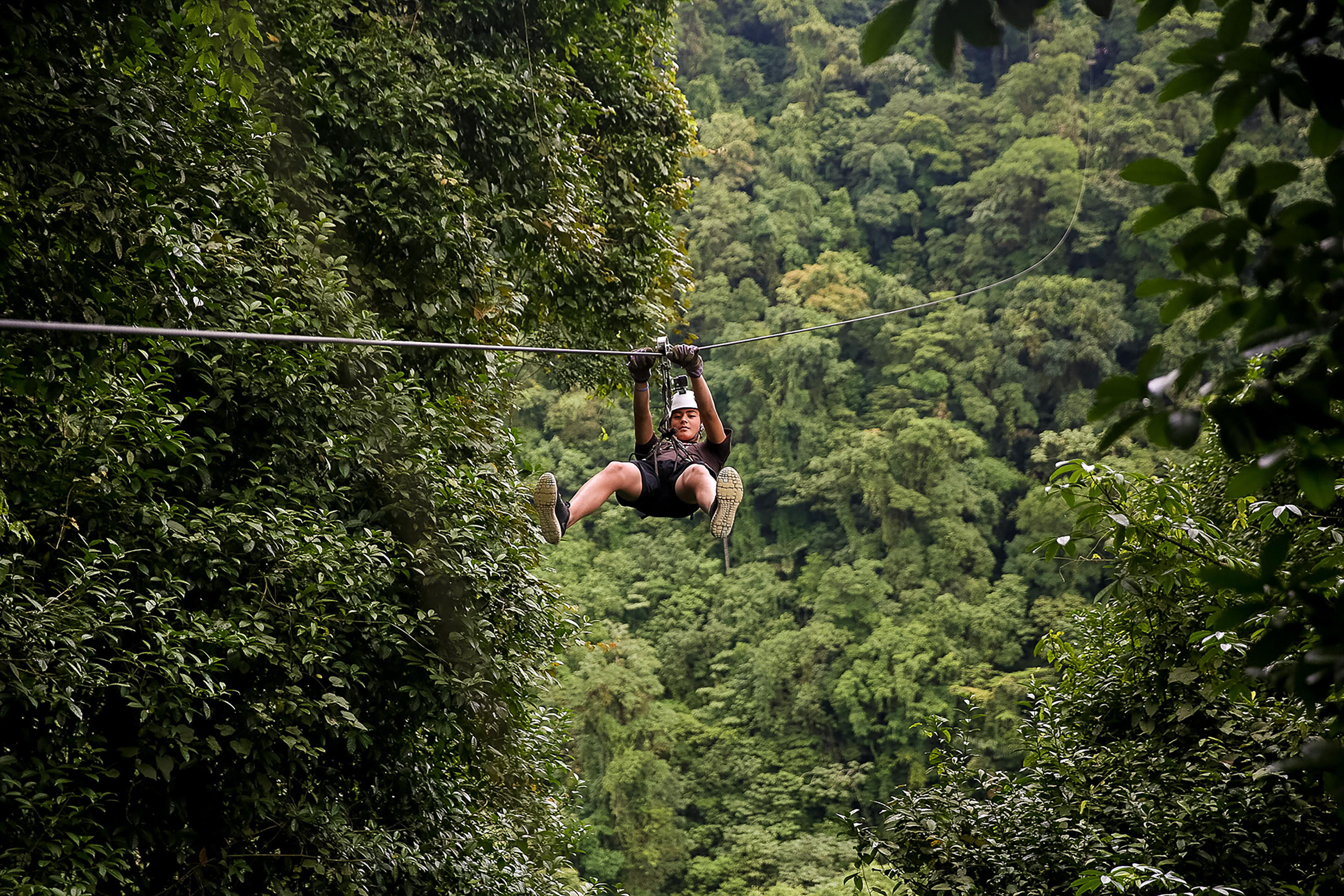 A student ziplines over a lush rainforest canopy in Costa Rica