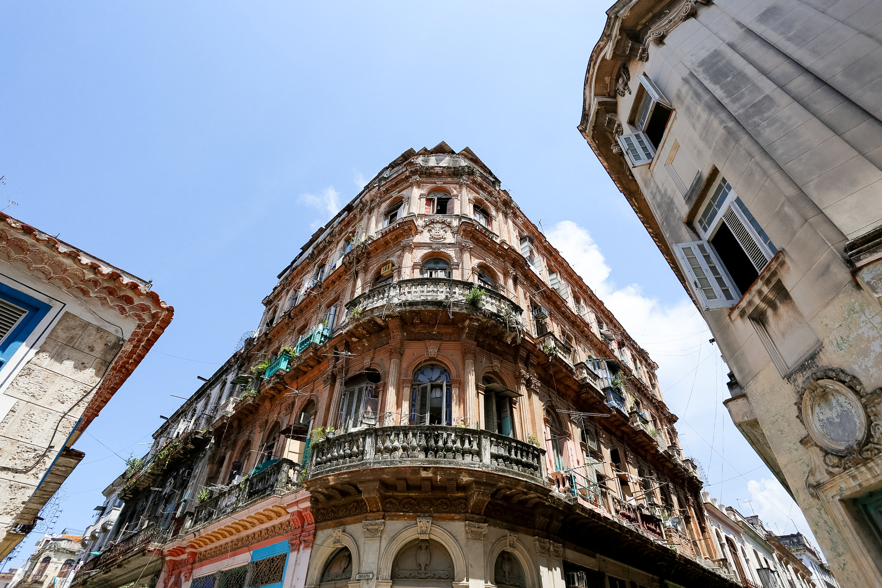 Ornate balconies wrap the corner of a weathered colonial building against a blue sky