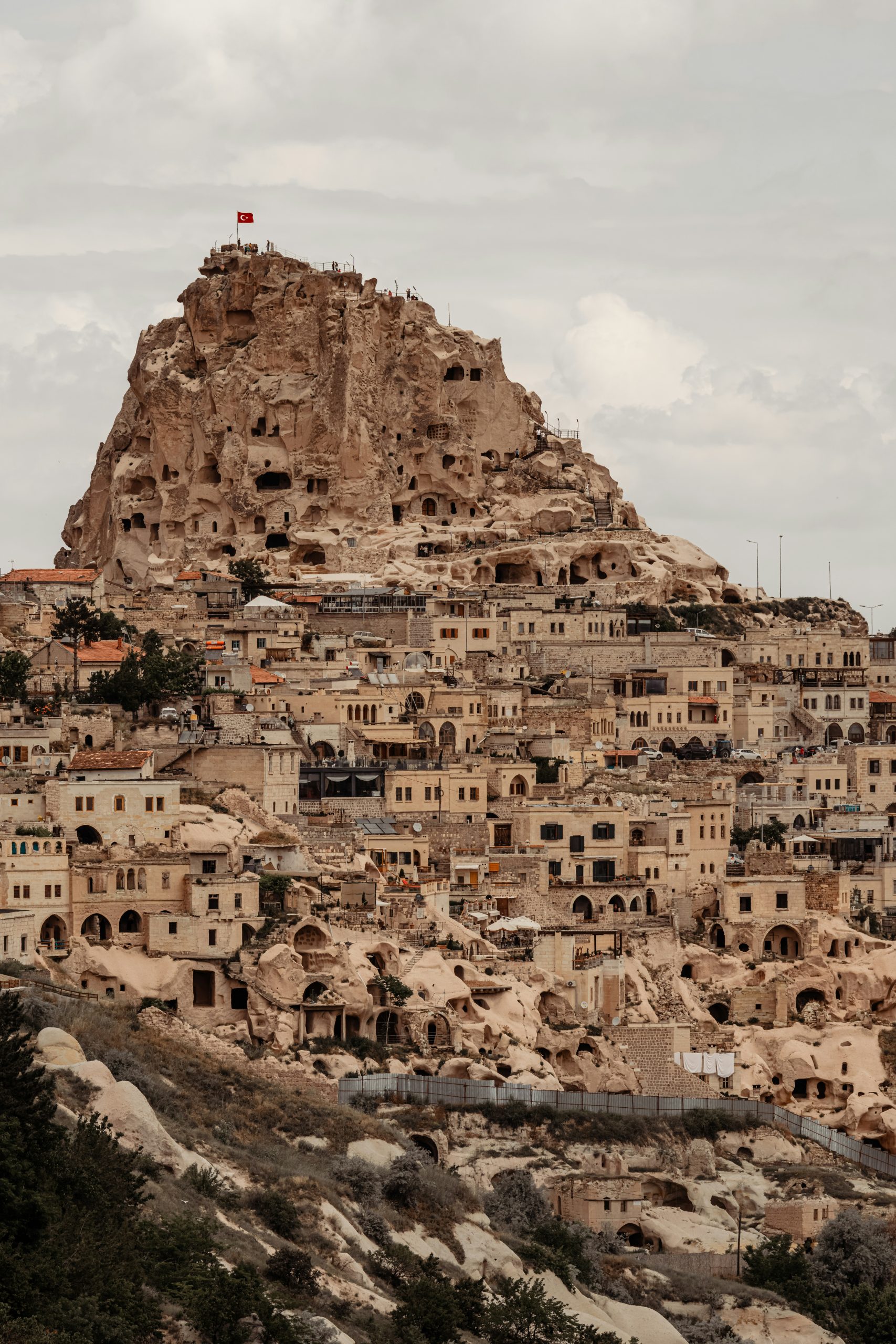 Uçhisar's rock-cut castle rising above the cave houses and stone buildings of the village below it.