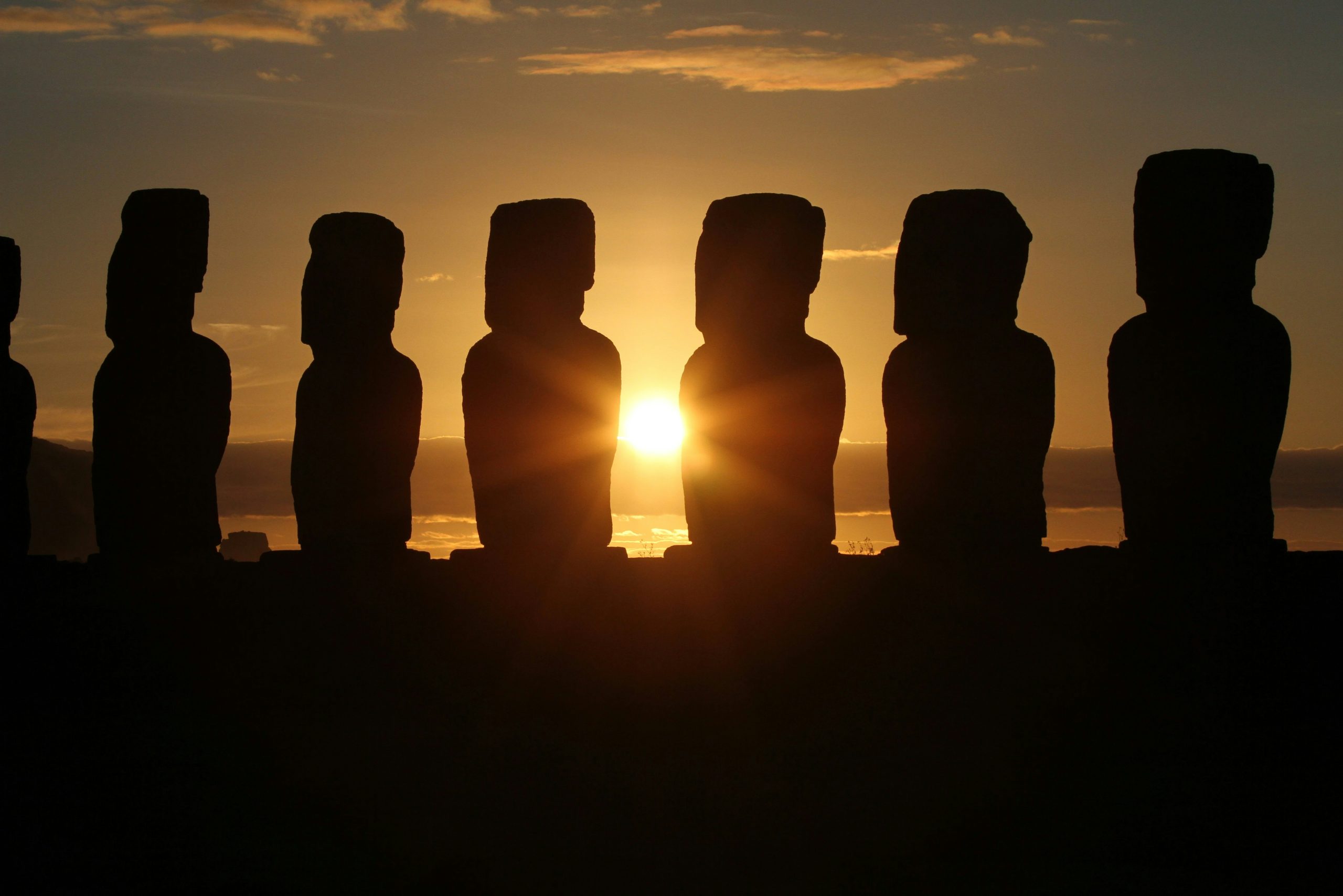 Landscape photo of a sunset with Maoi statues found in Easter Island, Chile.