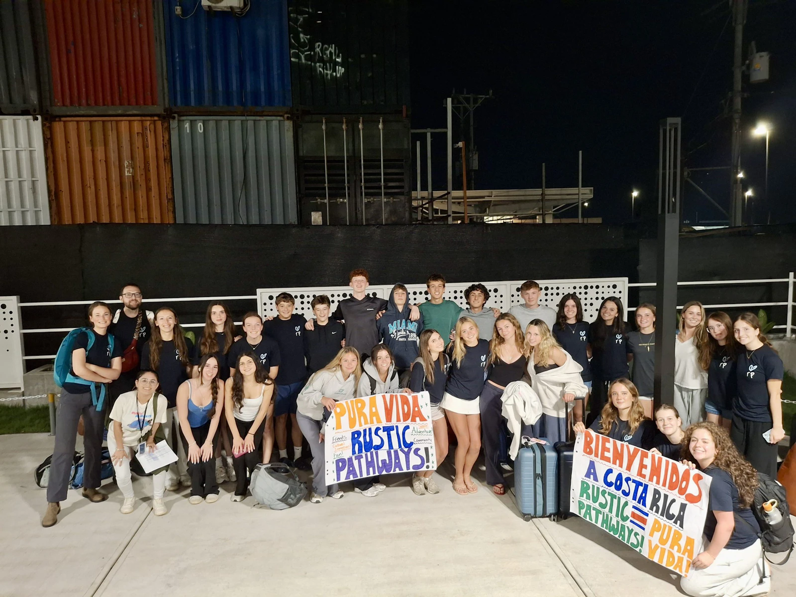 Students hold welcome signs at night outside the airport in San José, Costa Rica