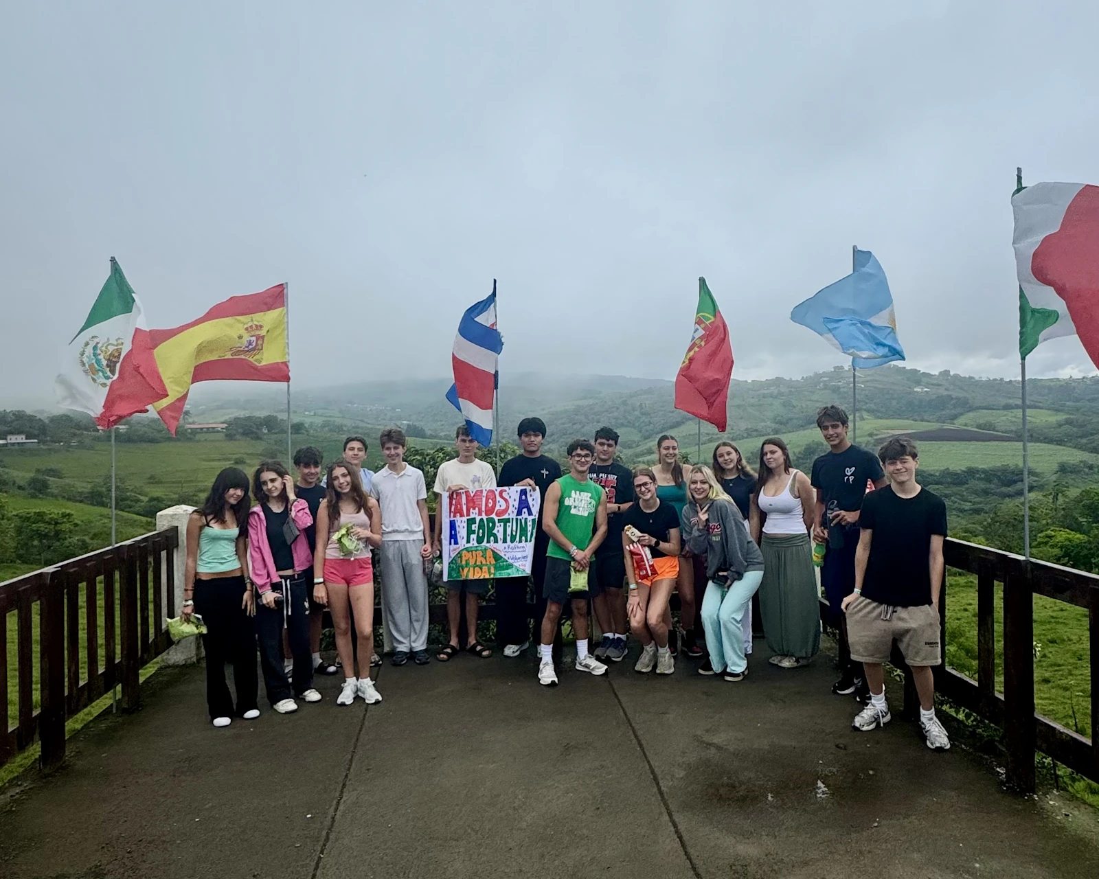 Students hold up a handmade sign on a deck lined with national flags in Costa Rica