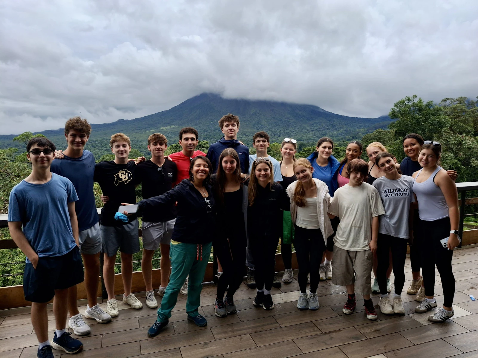 A Rustic Pathways group stands on a deck with Arenal Volcano behind them in Costa Rica