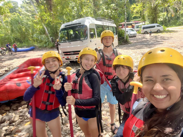 Smiling students in rafting helmets and life vests pose for a selfie before rafting in Costa Rica