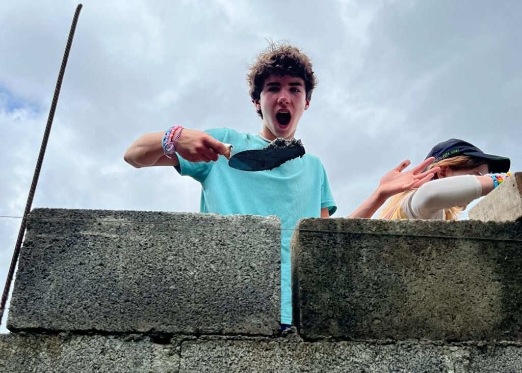 Teen laying concrete on a service learning trip