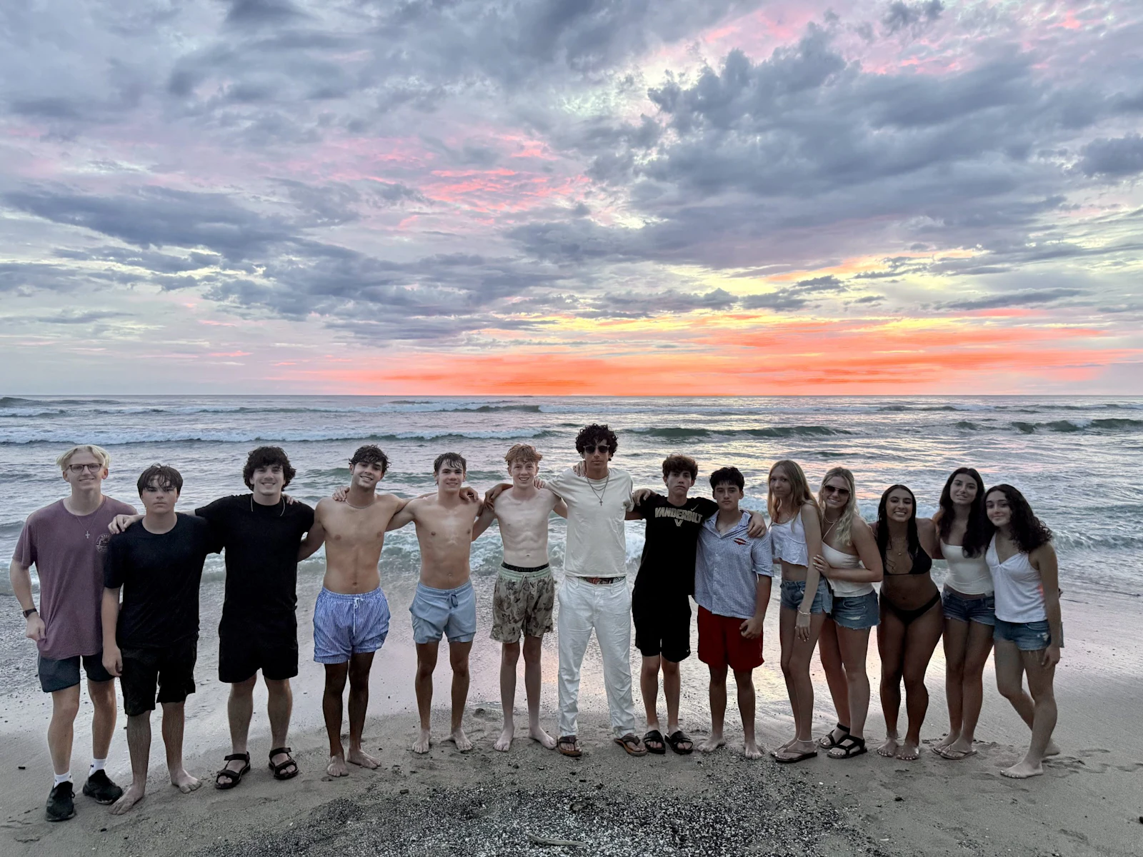 A Rustic Pathways group stands arm in arm on a Costa Rica beach at sunset