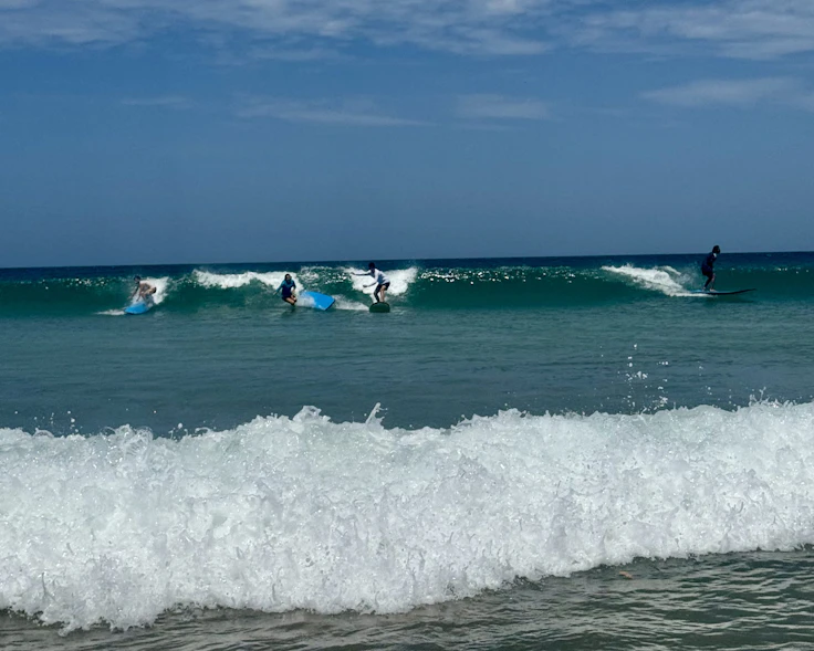 Students ride small waves on surfboards off Playa Avellanas in Costa Rica