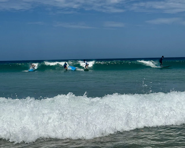 Students ride small waves on surfboards off Playa Avellanas in Costa Rica
