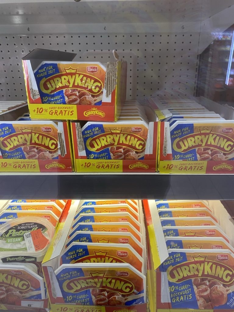 A supermarket shelf stocked with Curry King currywurst packages.