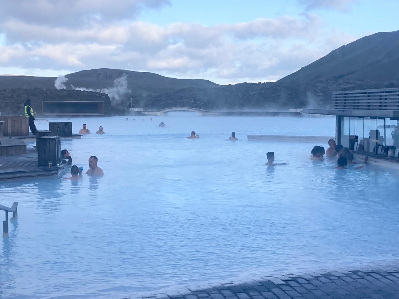 Students soak in a steaming geothermal lagoon in Iceland, with hills in the background