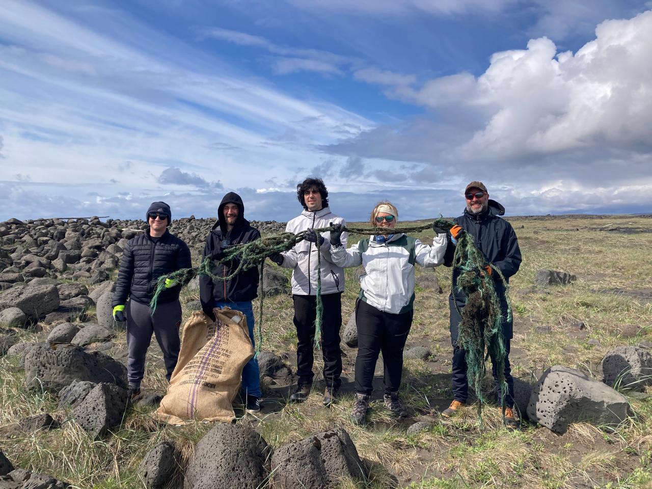 Students hold up tangled rope and debris collected from a rocky Icelandic coastline