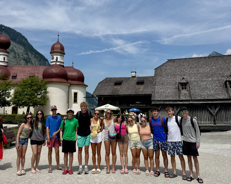 A Rustic Pathways student group stands in front of the red onion domes of St. Bartholomew's Church on the Königssee