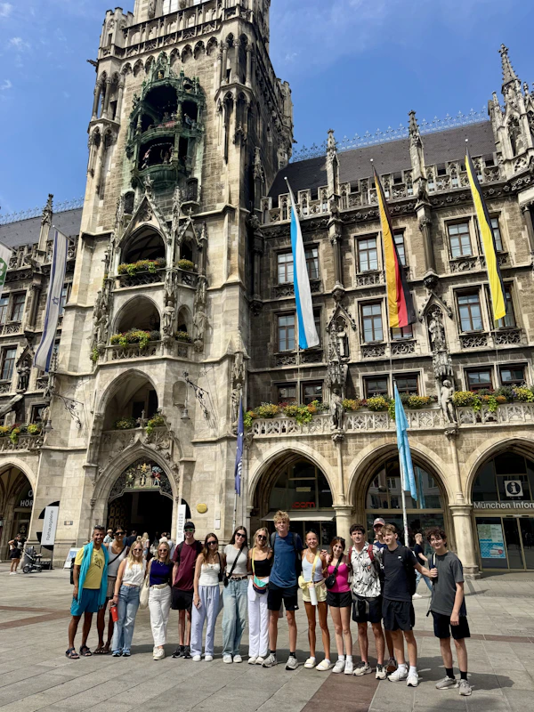 A Rustic Pathways student group stands in front of Munich's New Town Hall, hung with flags