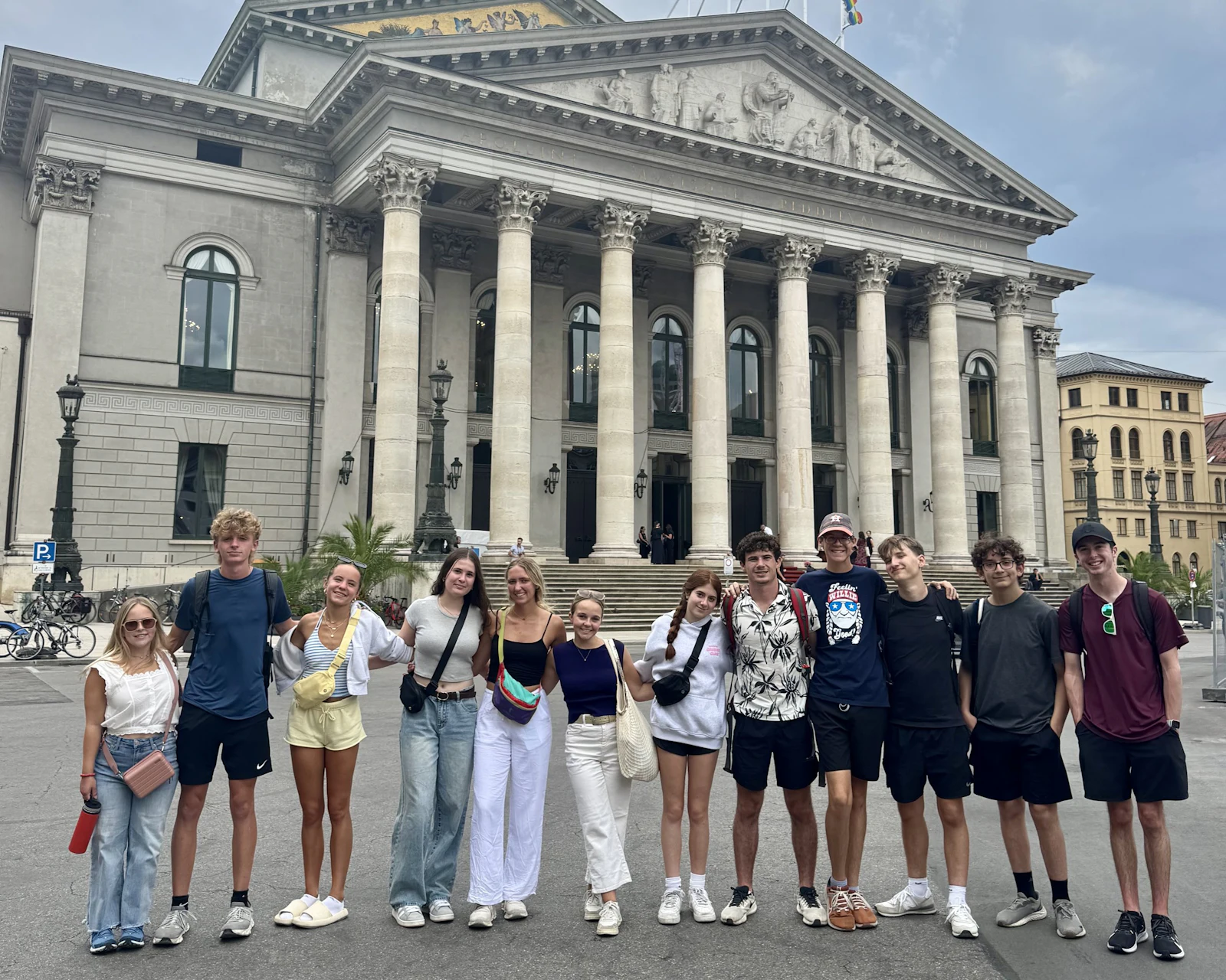 Teen travelers stand together in front of the Munich National Theatre