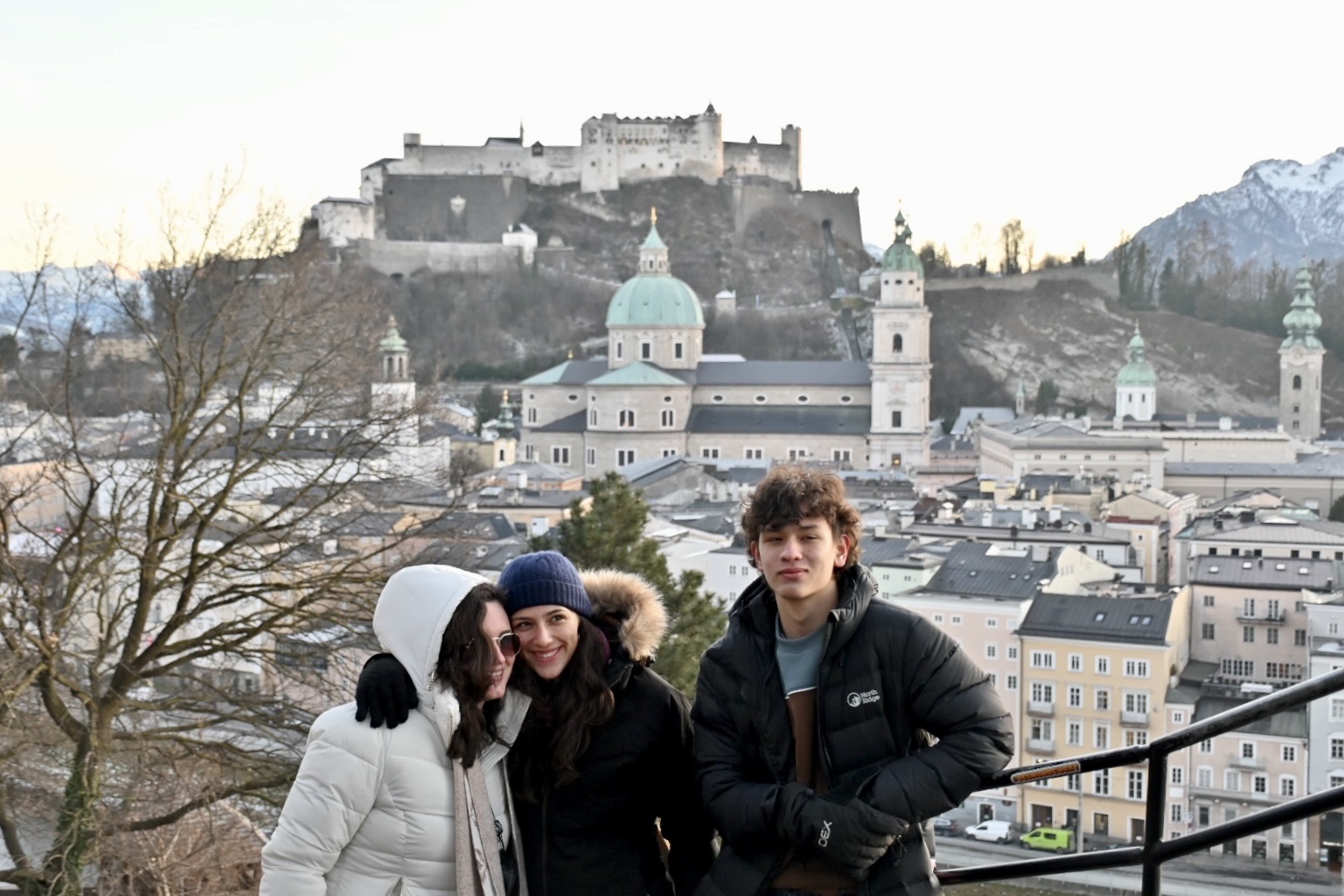 Student travelers pose for a photo above Salzburg, Austria, with Hohensalzburg Fortress and Alpine scenery in the background, on a teen travel program.