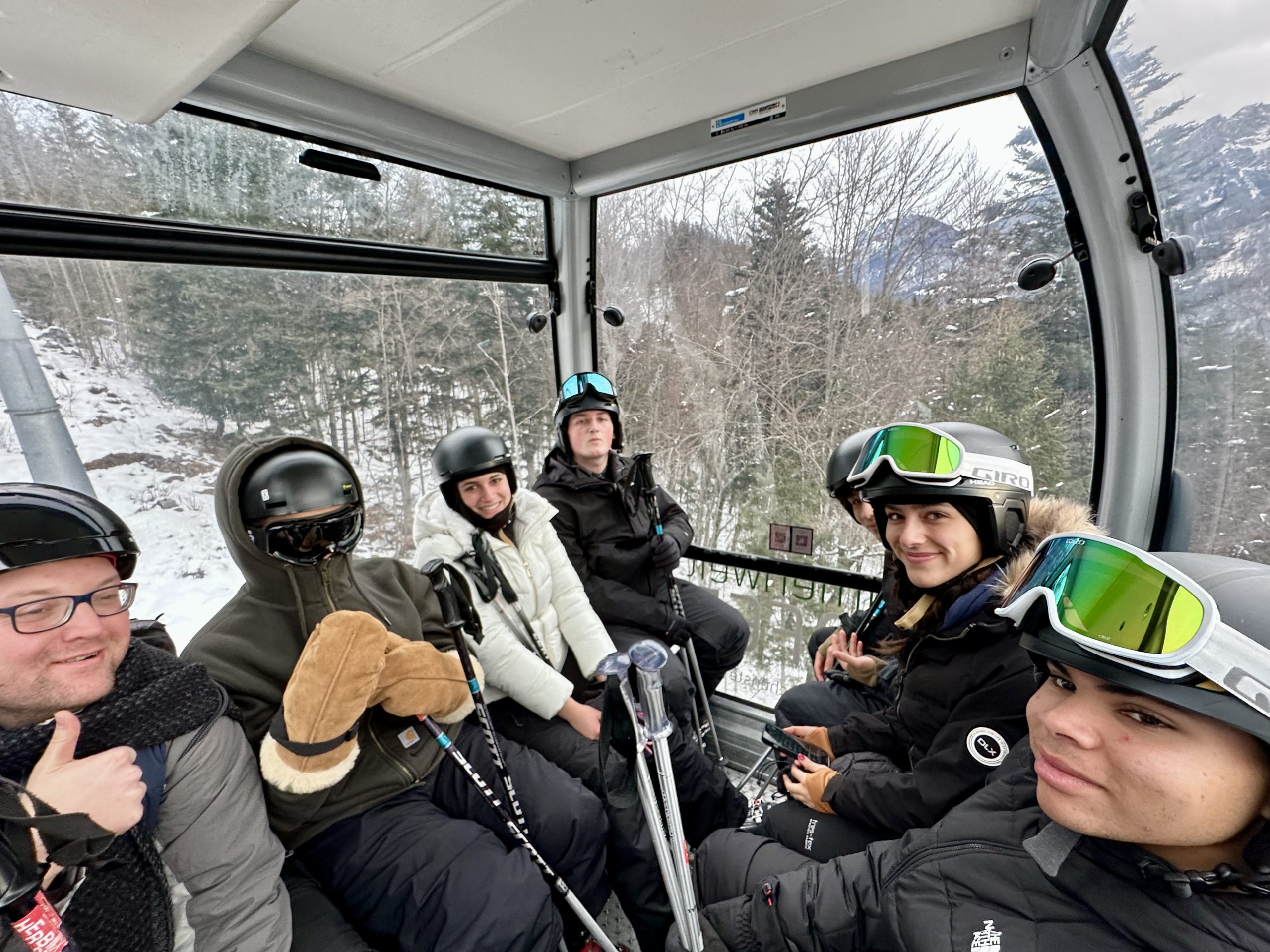 Student travelers ride a gondola ski lift in the Bavarian Alps, ready for a day of skiing on their Rustic Pathways teen travel program in Germany.