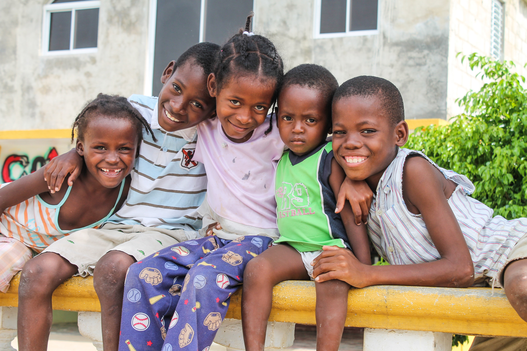 Students sit together on a wall, smiling for the camera