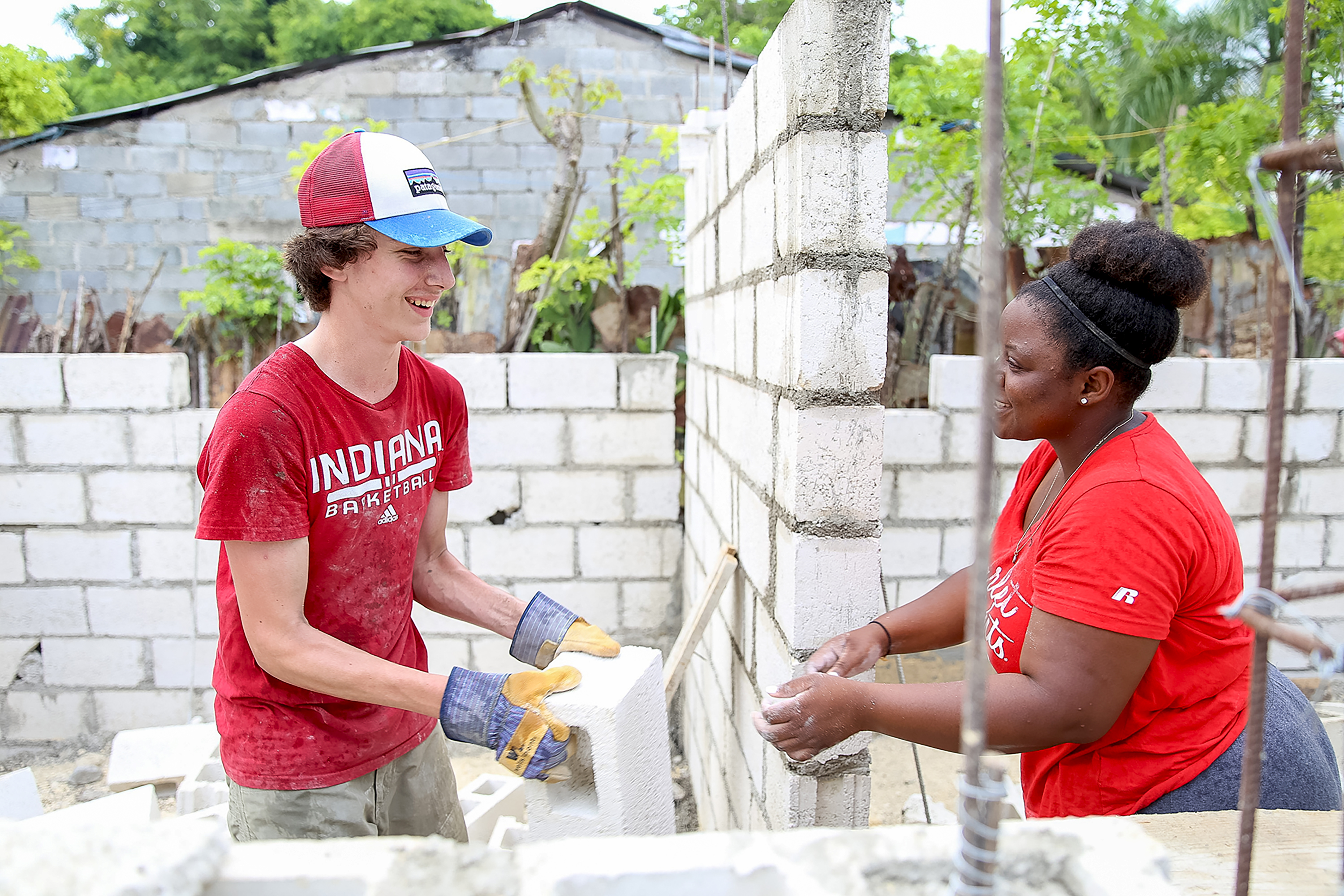 A student and a local resident laugh together at a cinder block construction site in Dominican Republic