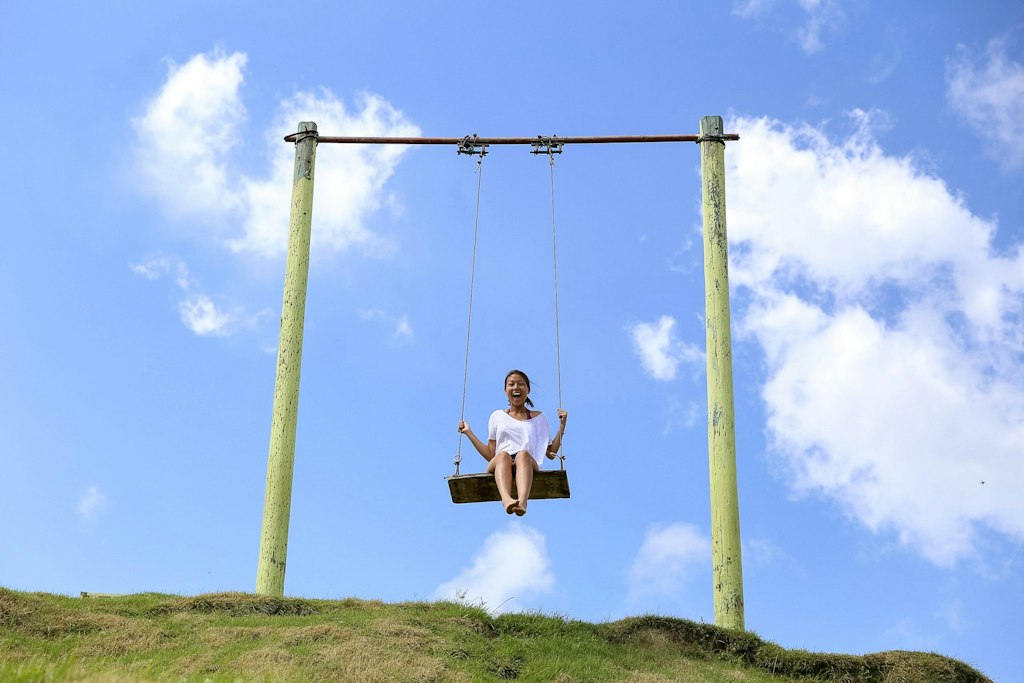 Student enjoying a swing under the blue sky during a short-term volunteer abroad program that balances service and adventure.