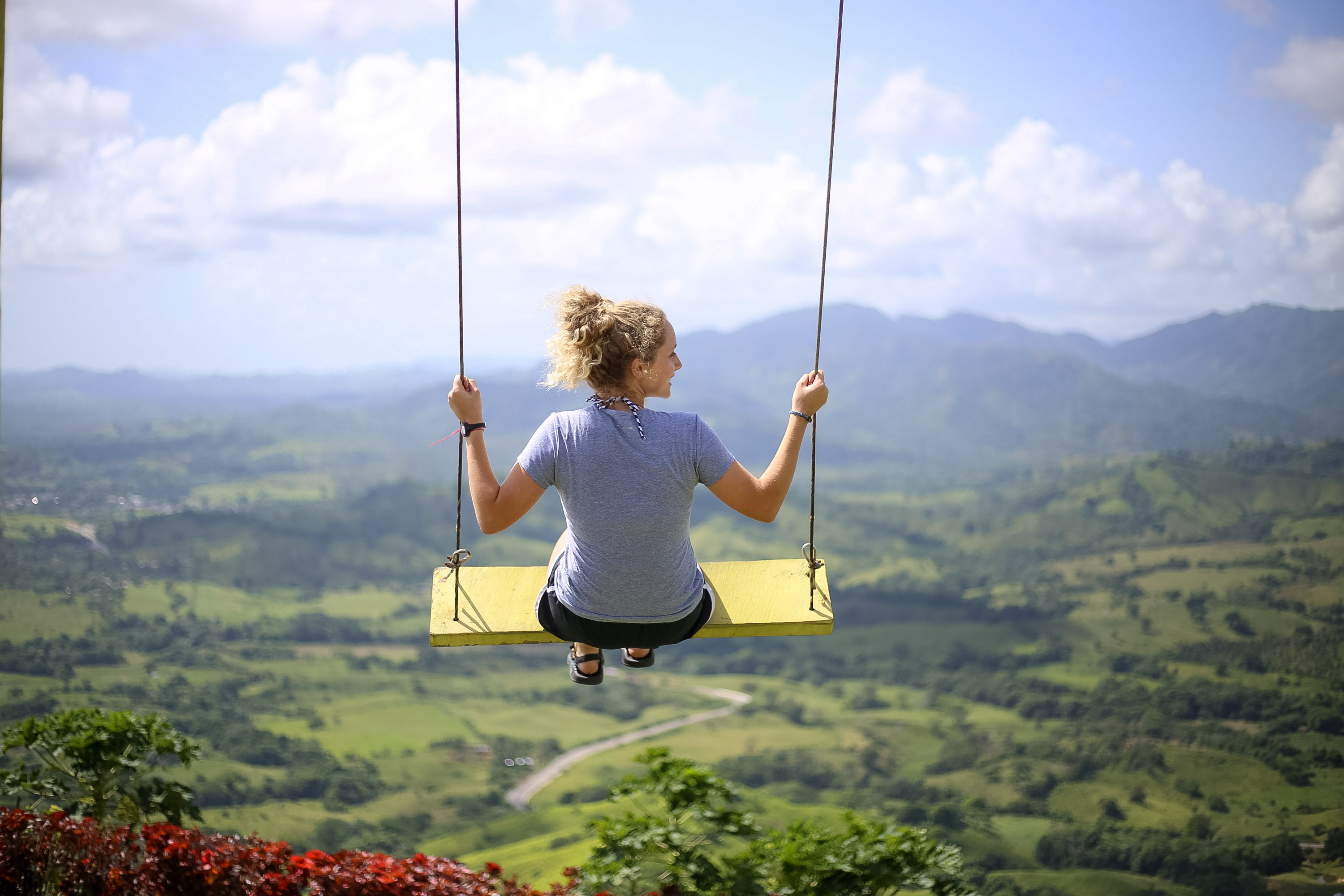 A student on a swing overlooks a green valley and mountains