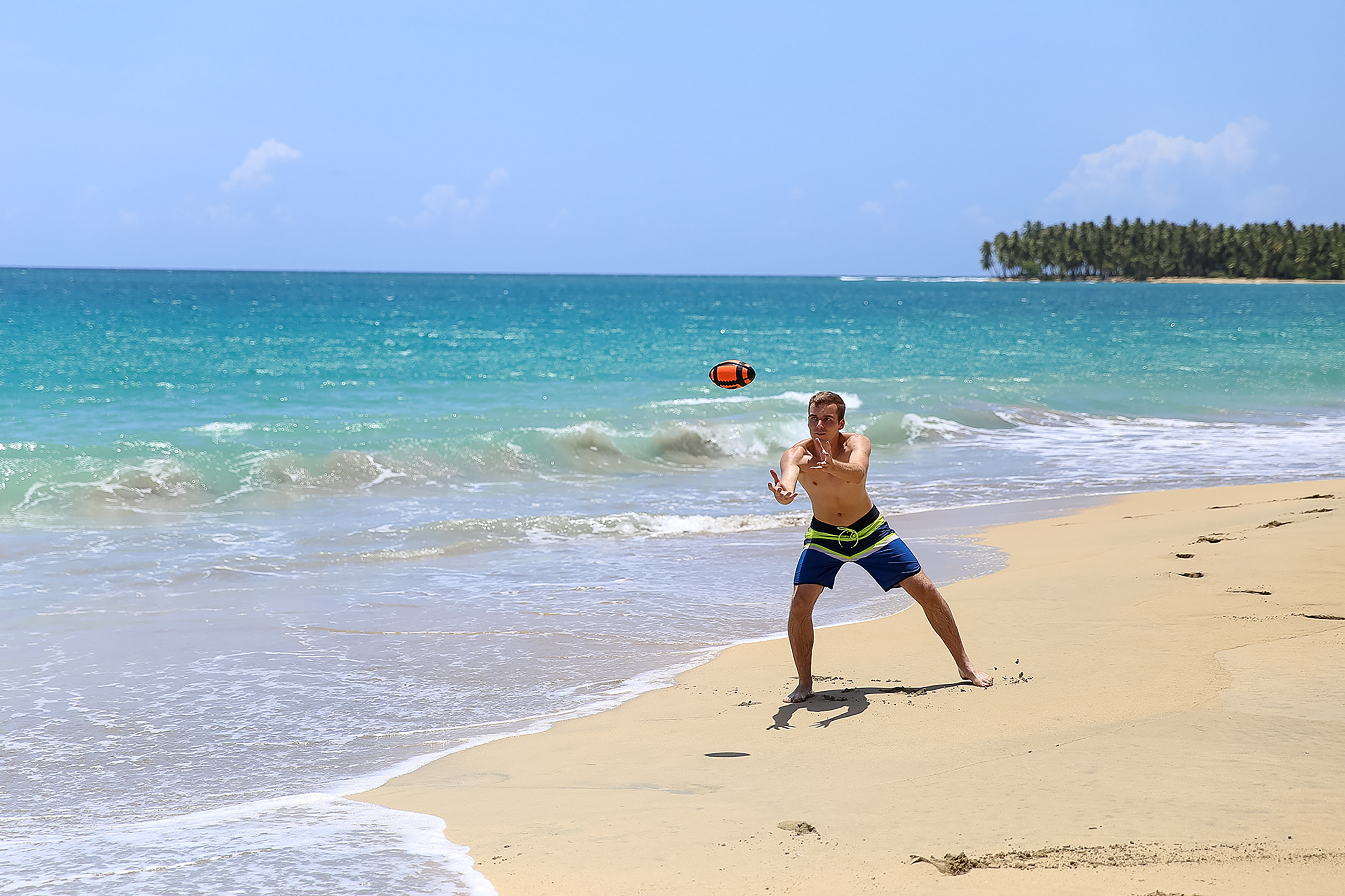 Student travelers toss a ball while playing catch on the beach