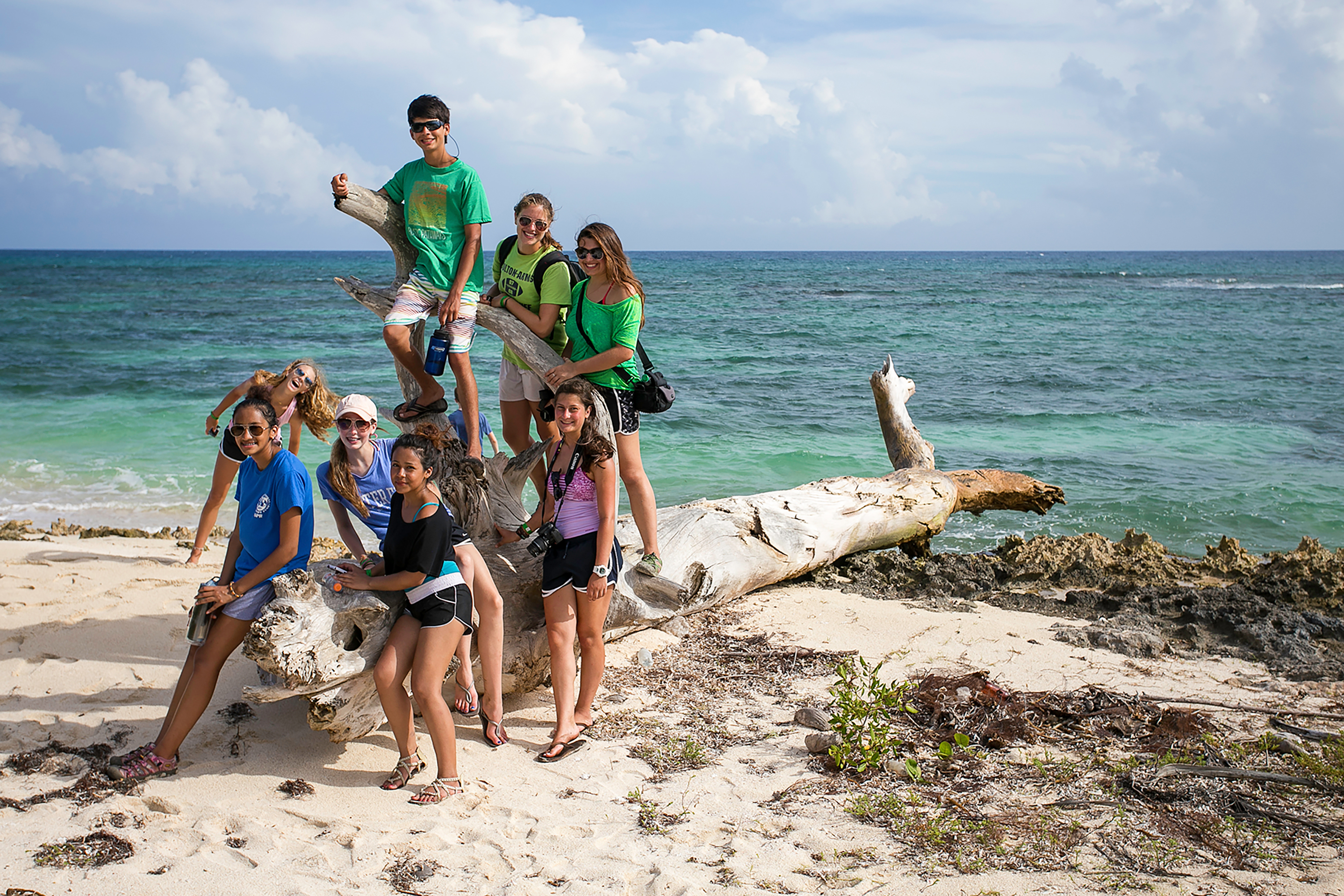 Students cleaning a beach and playing volleyball near turquoise water in the Dominican Republic