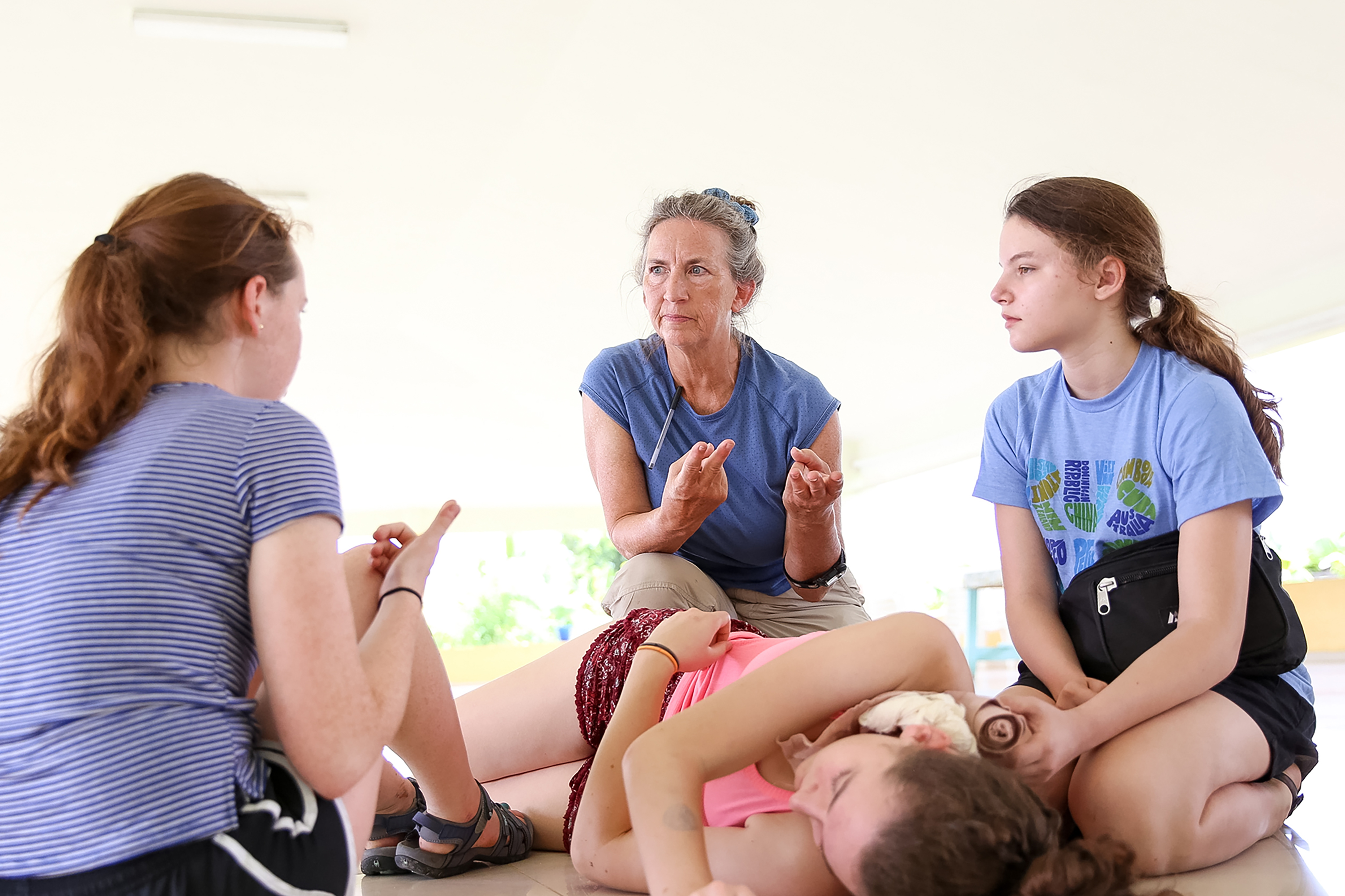 An instructor leads students through a discussion while seated on the ground