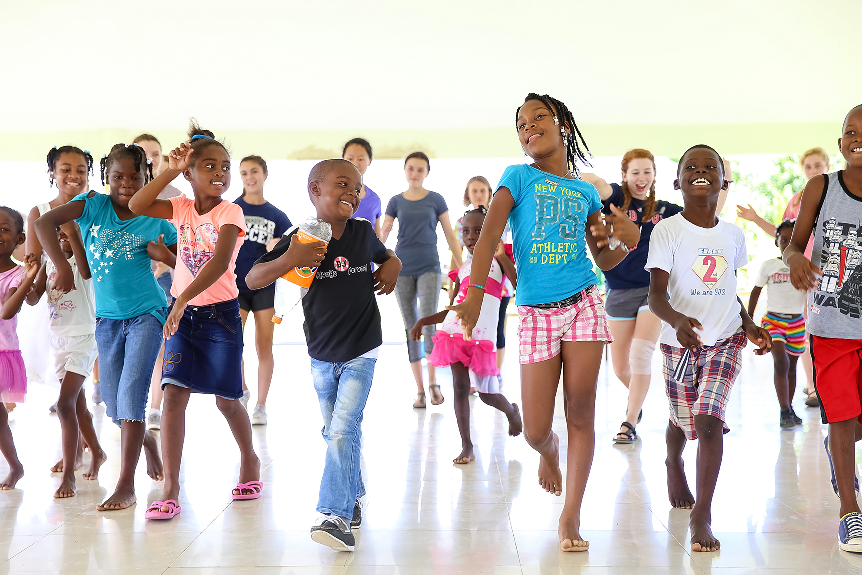 Local children dance together in a bright, open-air pavilion
