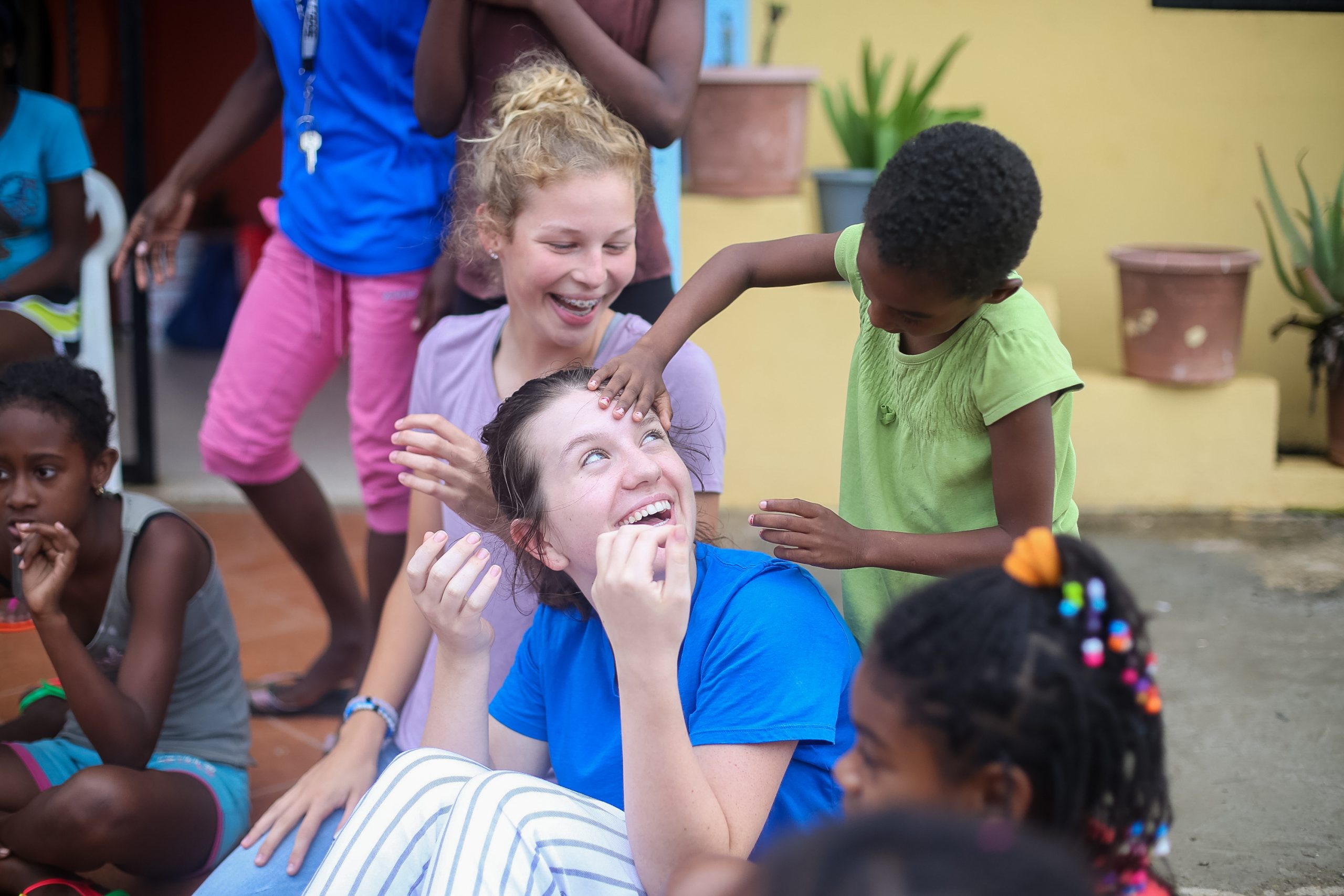 Students laugh and play with local children in a courtyard