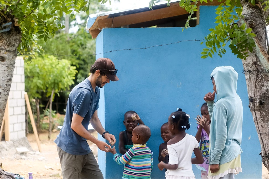 Public health volunteering abroad participants lead outdoor health education activities with local children to promote global wellness.