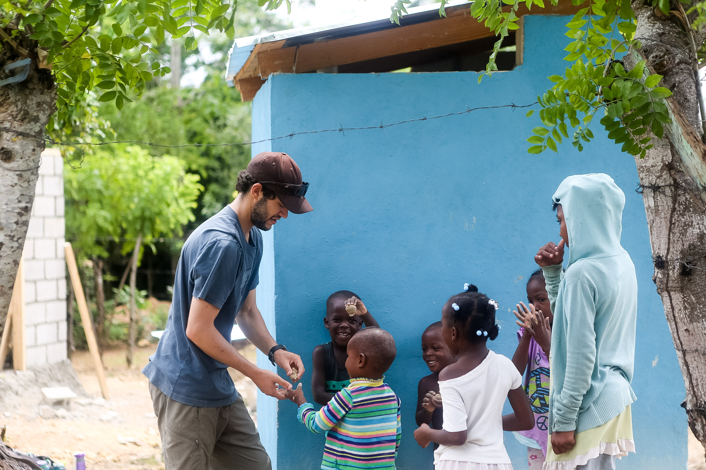 Students greet local children outside a blue building