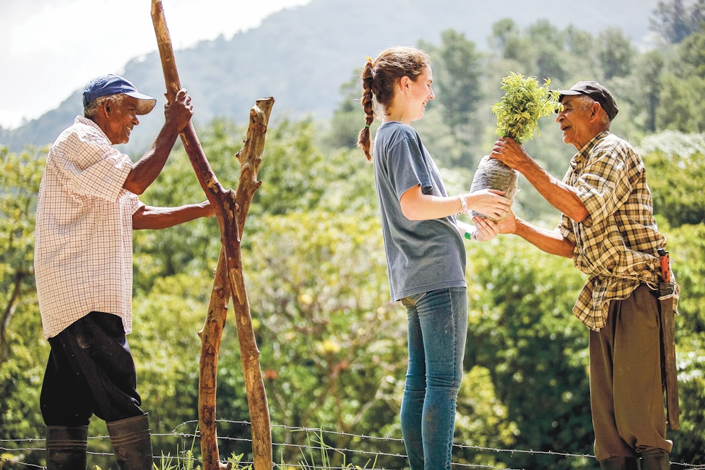 A young woman participating in climate change volunteering abroad by helping with farming activities, working in the fields alongside others to promote sustainable agriculture and environmental awareness.