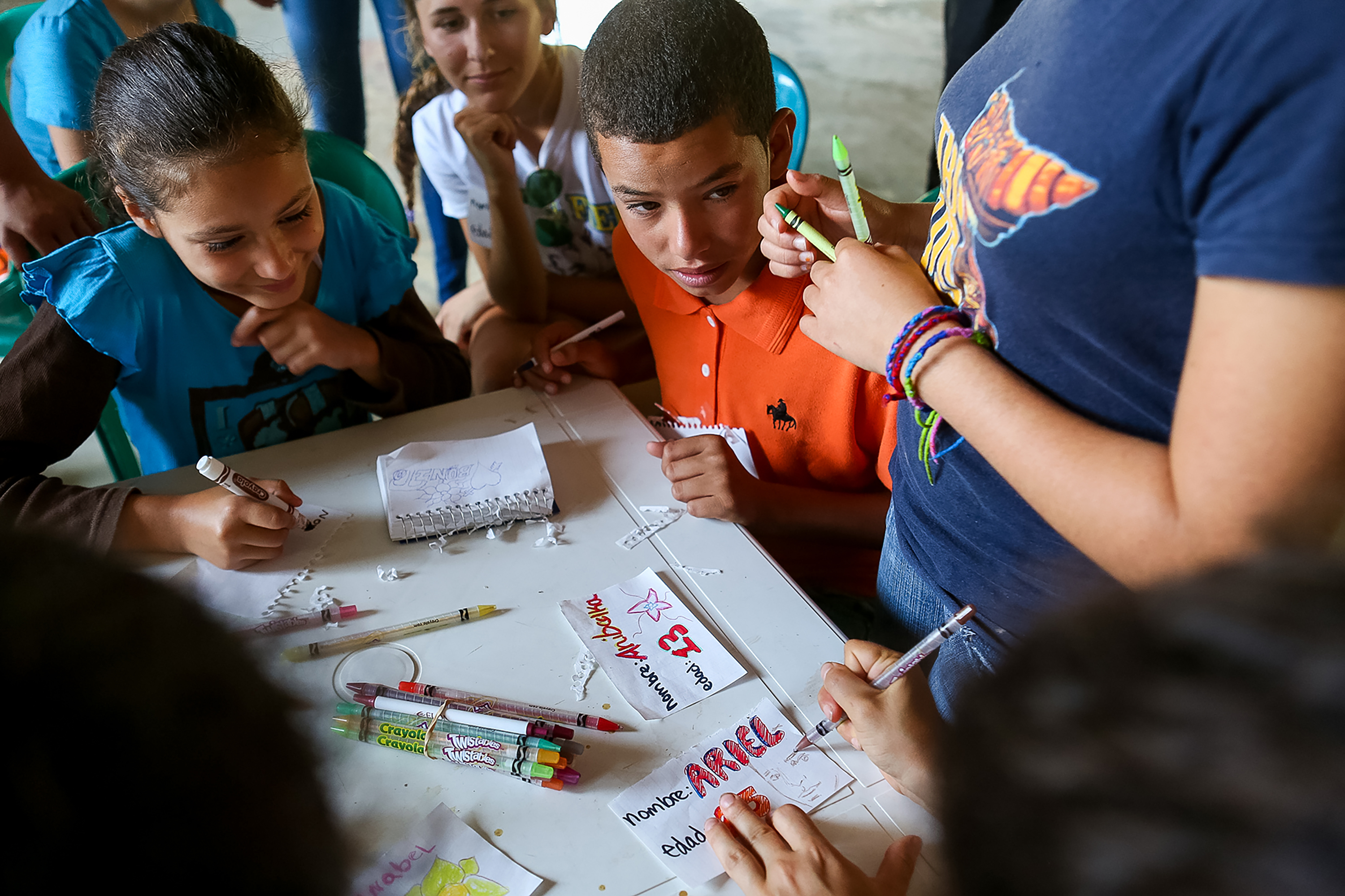 Student travelers gather around a table making colorful name cards with markers