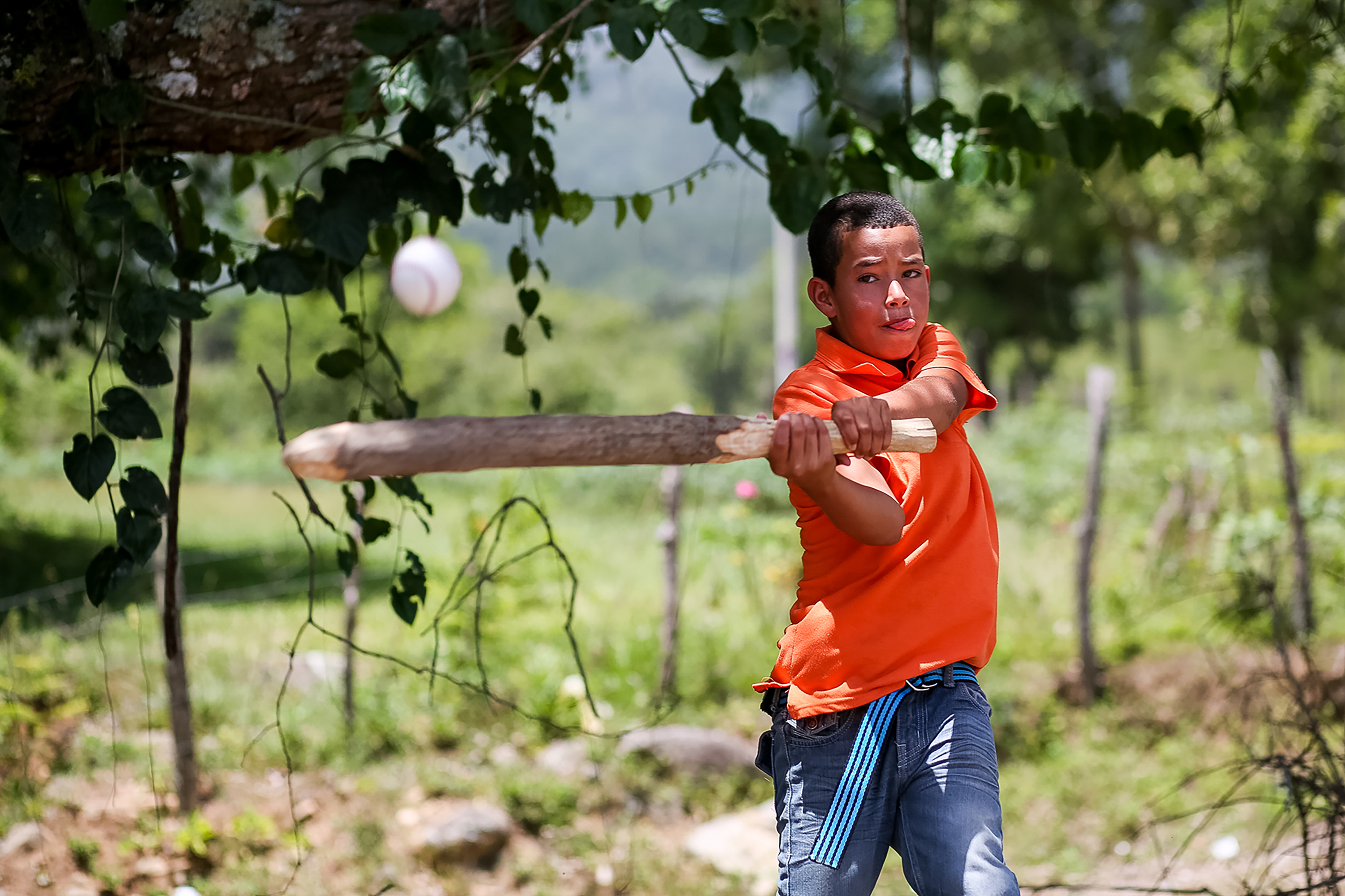 A student swings a wooden bat at a ball outdoors