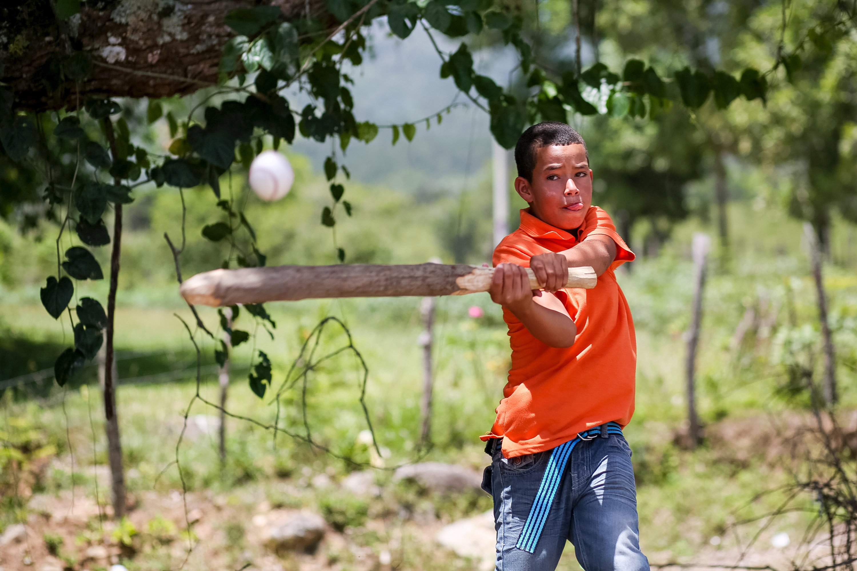 A student swings a wooden bat at a pitched ball outdoors