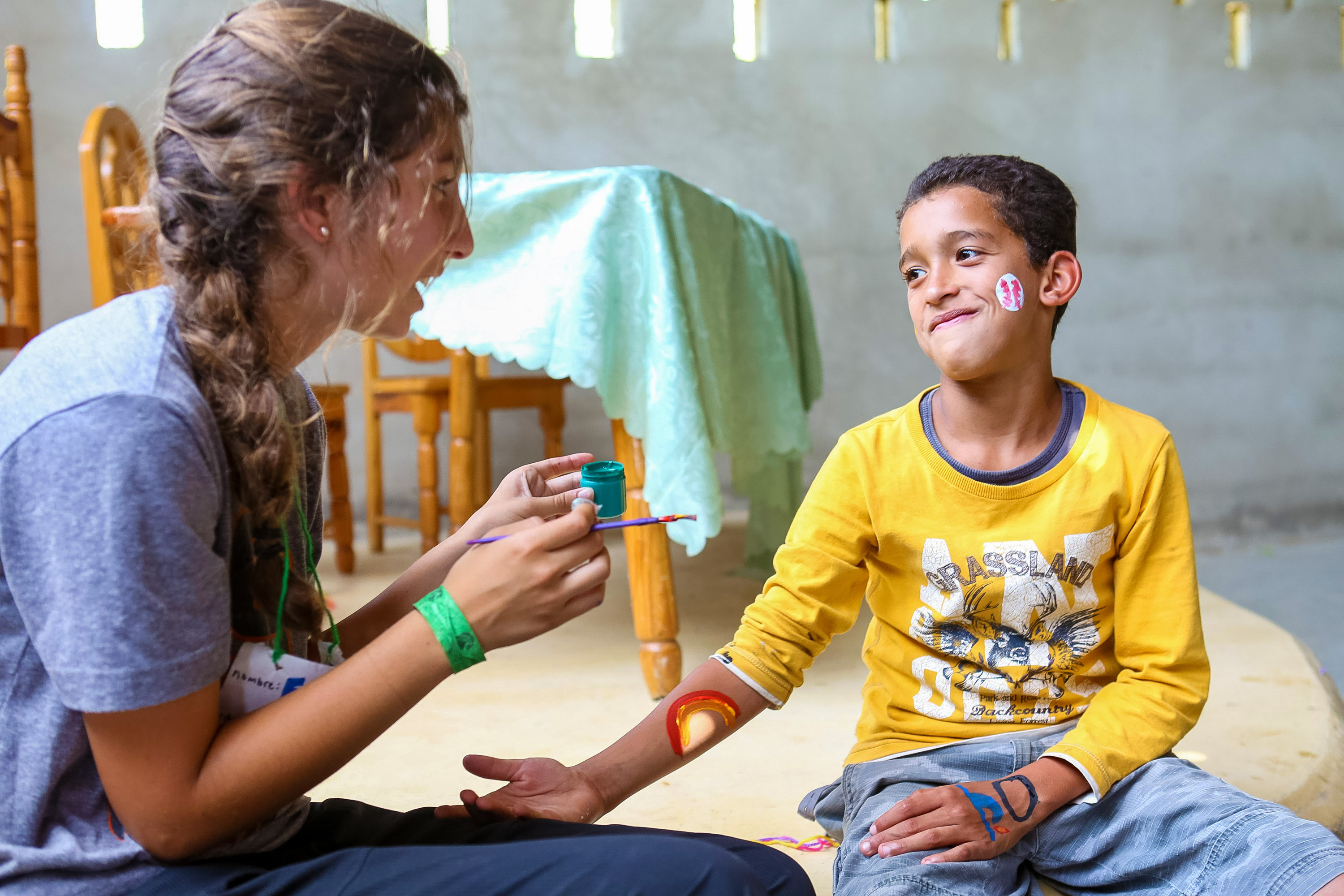 A student paints a child's face with colorful designs