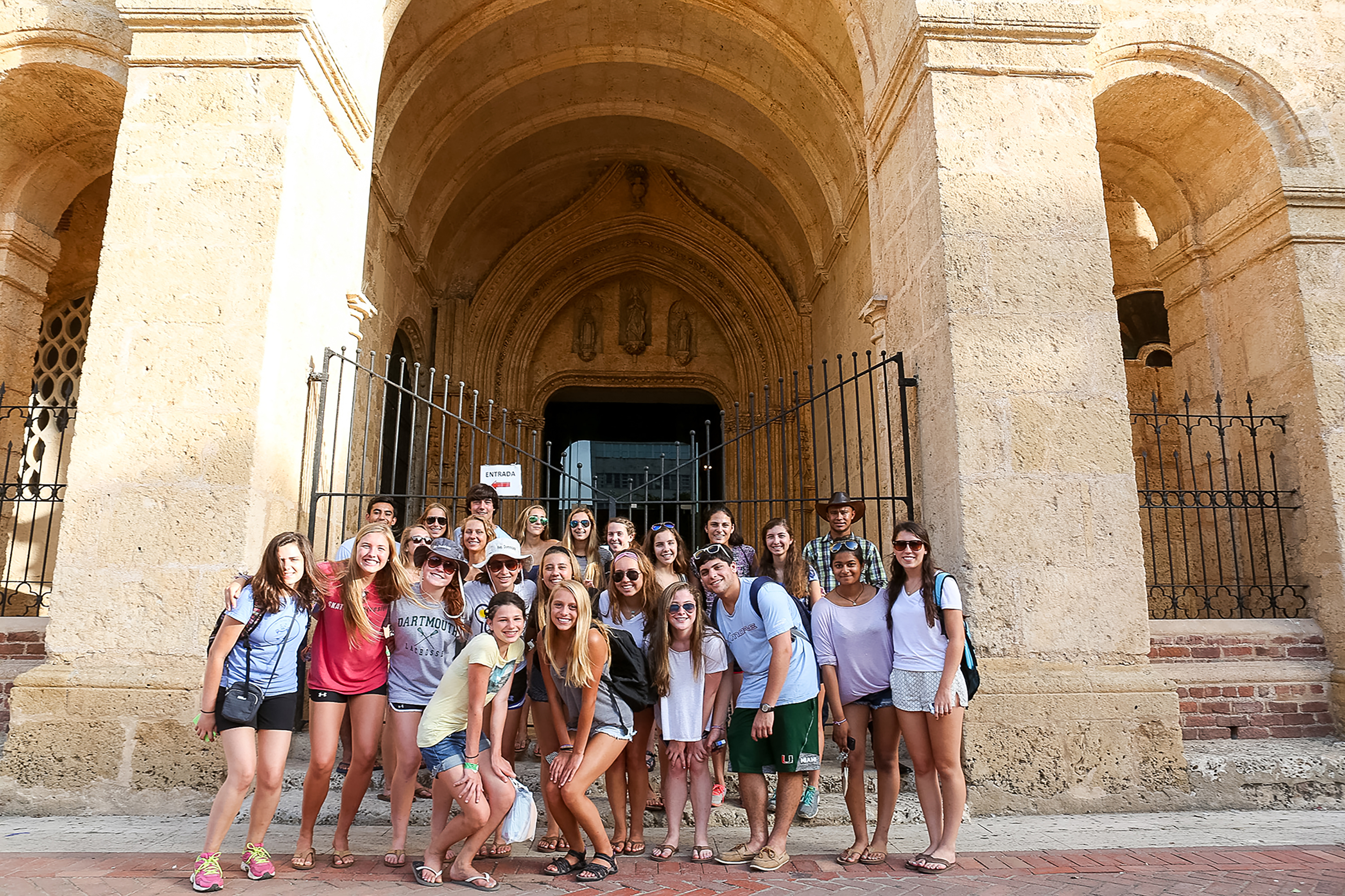Students pose together beneath an arched stone entrance in the Colonial Zone