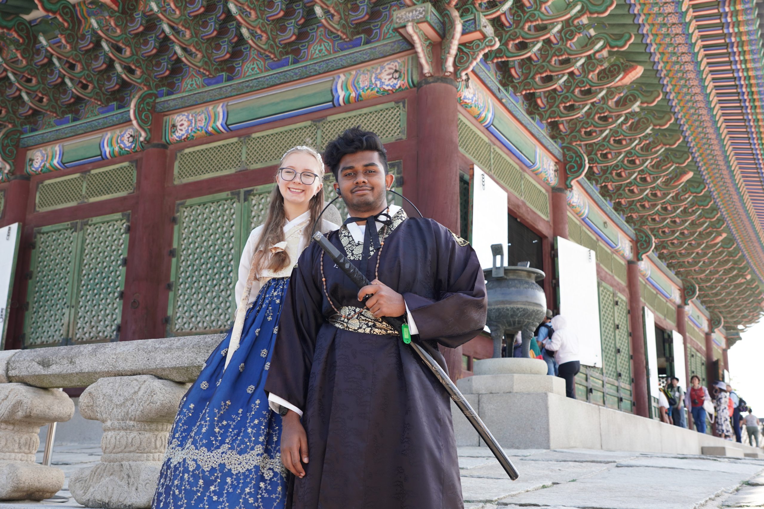 A boy and a girl in hanbok smile in front of one of the buildings inside Gyeongbokgung Palace in Seoul.