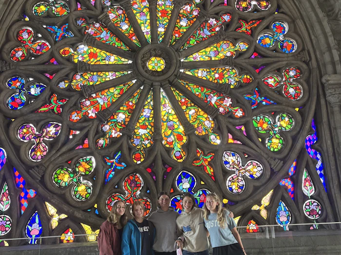 Students stand beneath a large stained-glass rose window inside a stone basilica in Quito.