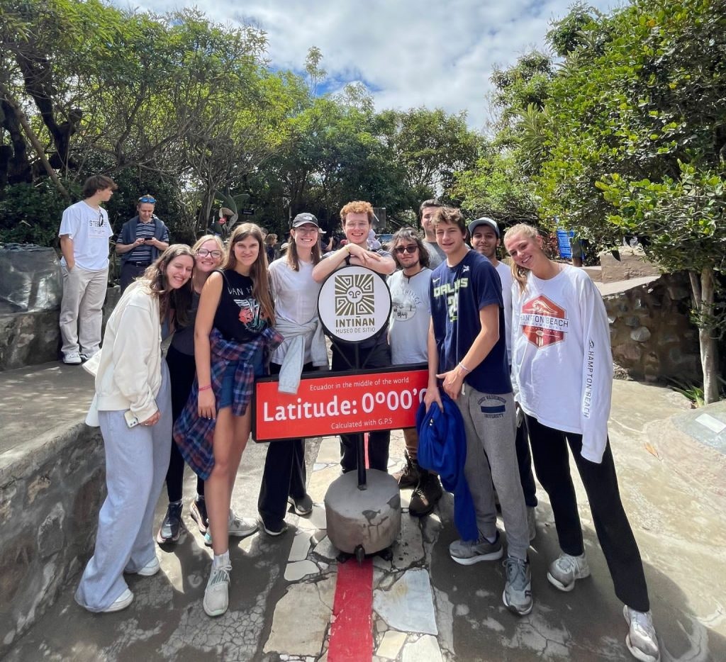 A group of teen travelers pose at the middle of the world monument in Quito Ecuador on a teen tour.