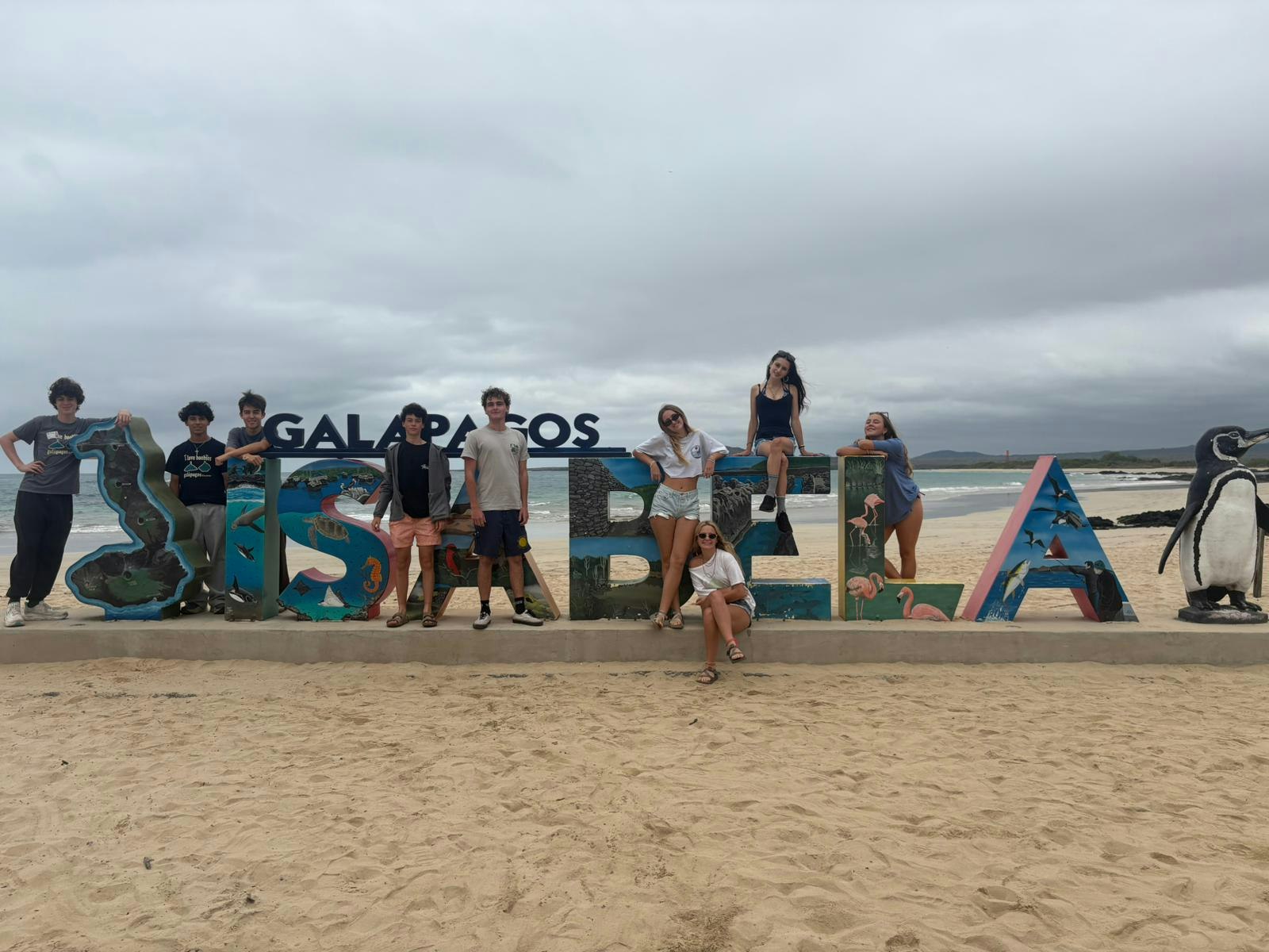 Students posing with the Isabela sign on Isabela Island in the Galápagos, Ecuador