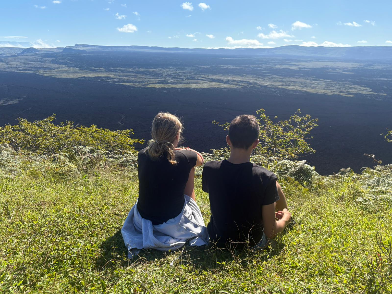 Two students sitting on a hillside in Yunguilla, looking at the valleys below