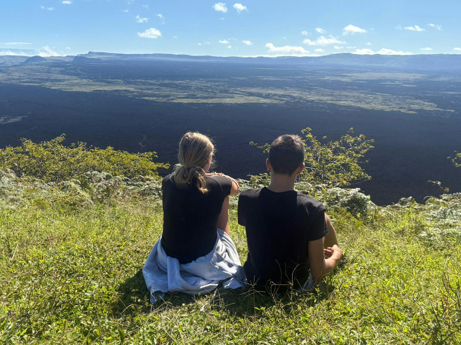 Two students sitting on a hillside in Yunguilla, looking at the valleys below