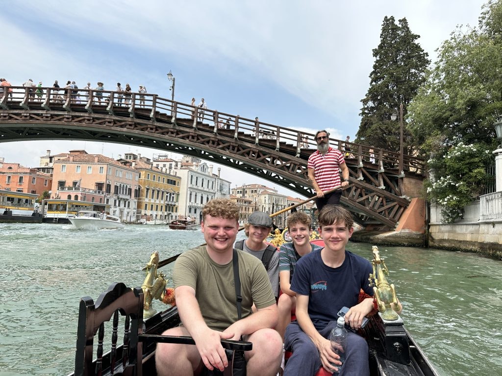 Four teen travelers enjoying a gondola ride in Venice during a Europe trip for students.