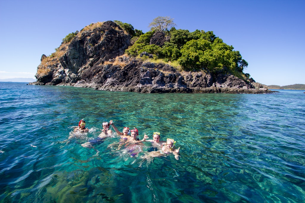 A group of students snorkeling near a small island.