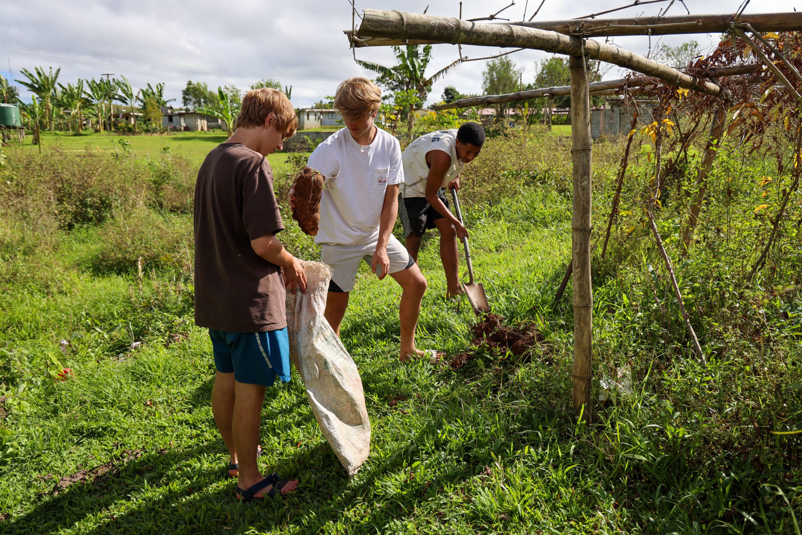 Students dig and haul debris during a community service project in Fiji